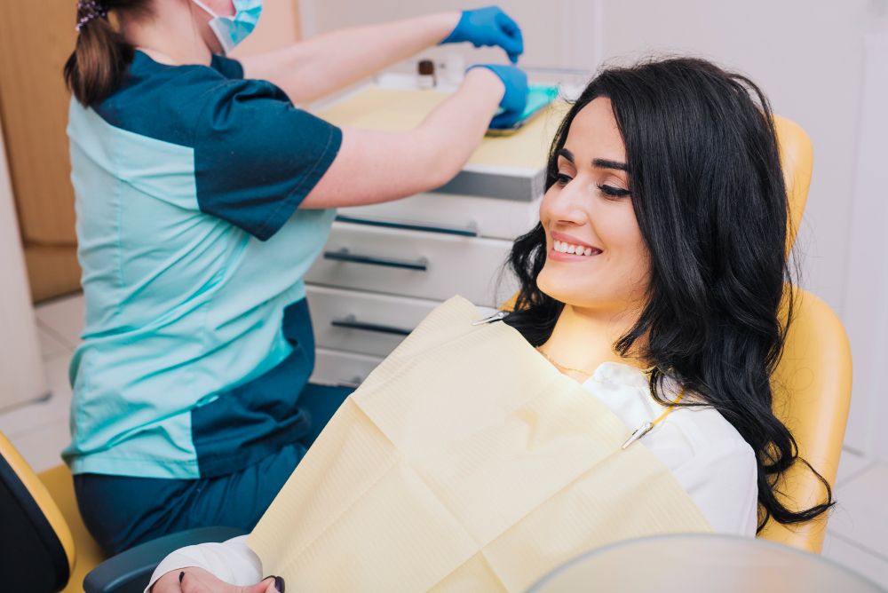 A woman in a dental chair with a dental assistant beside her