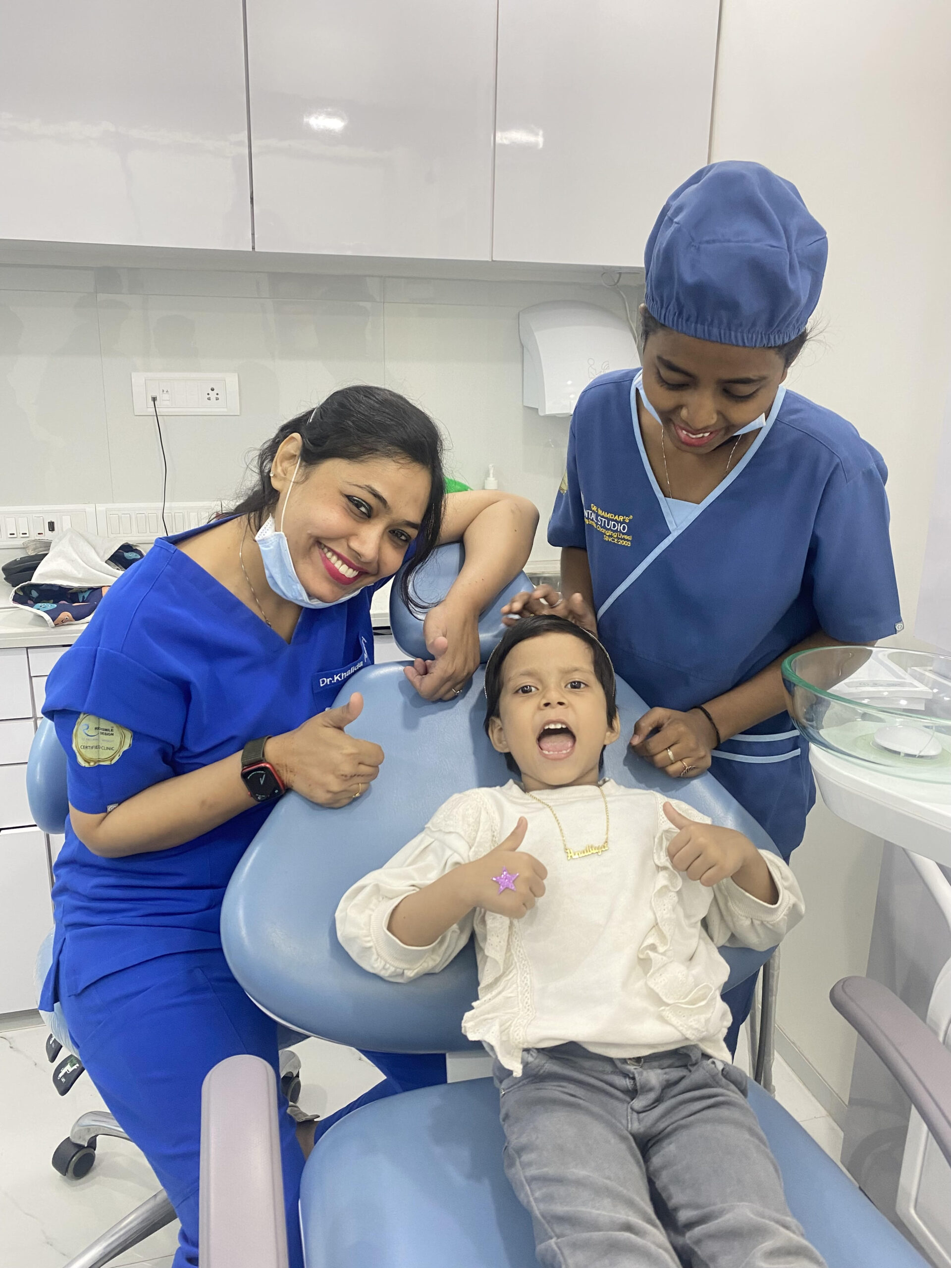 Dr. Khalida and a nurse with a small girl seated in a dental chair